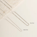 Flat lay of sterling silver cable and box chains displayed as styling options for Brooklyn Cross Necklace on neutral background for product detail.