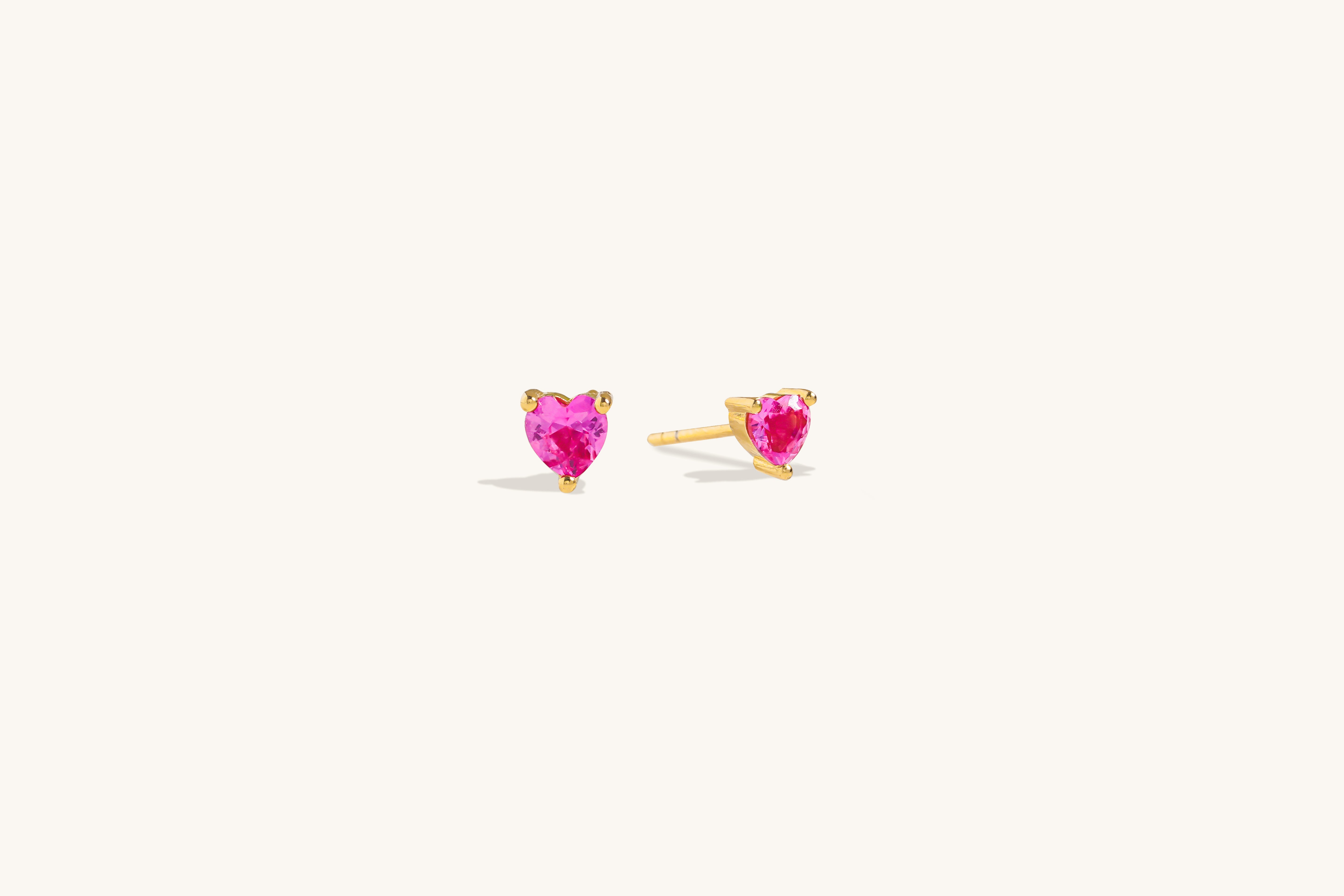 Ruby Liberty Stud Earrings in vermeil with ruby corundum stones shown from a side angle on neutral background to display prong setting detail clearly.