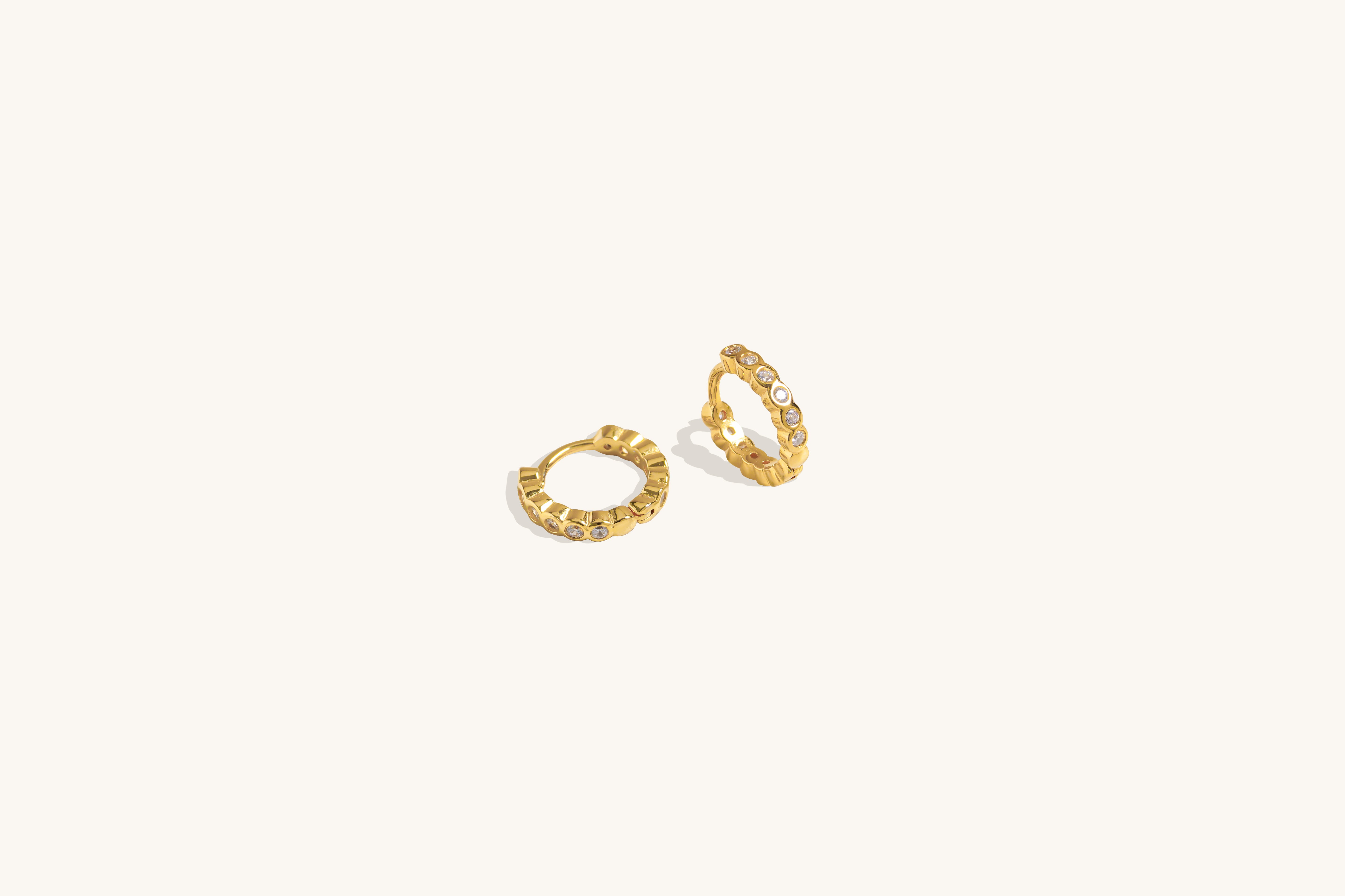 Twinkle Hoops earrings crafted in vermeil with cubic zirconia stones, photographed from a side angle on neutral background for hoop shape detail.
