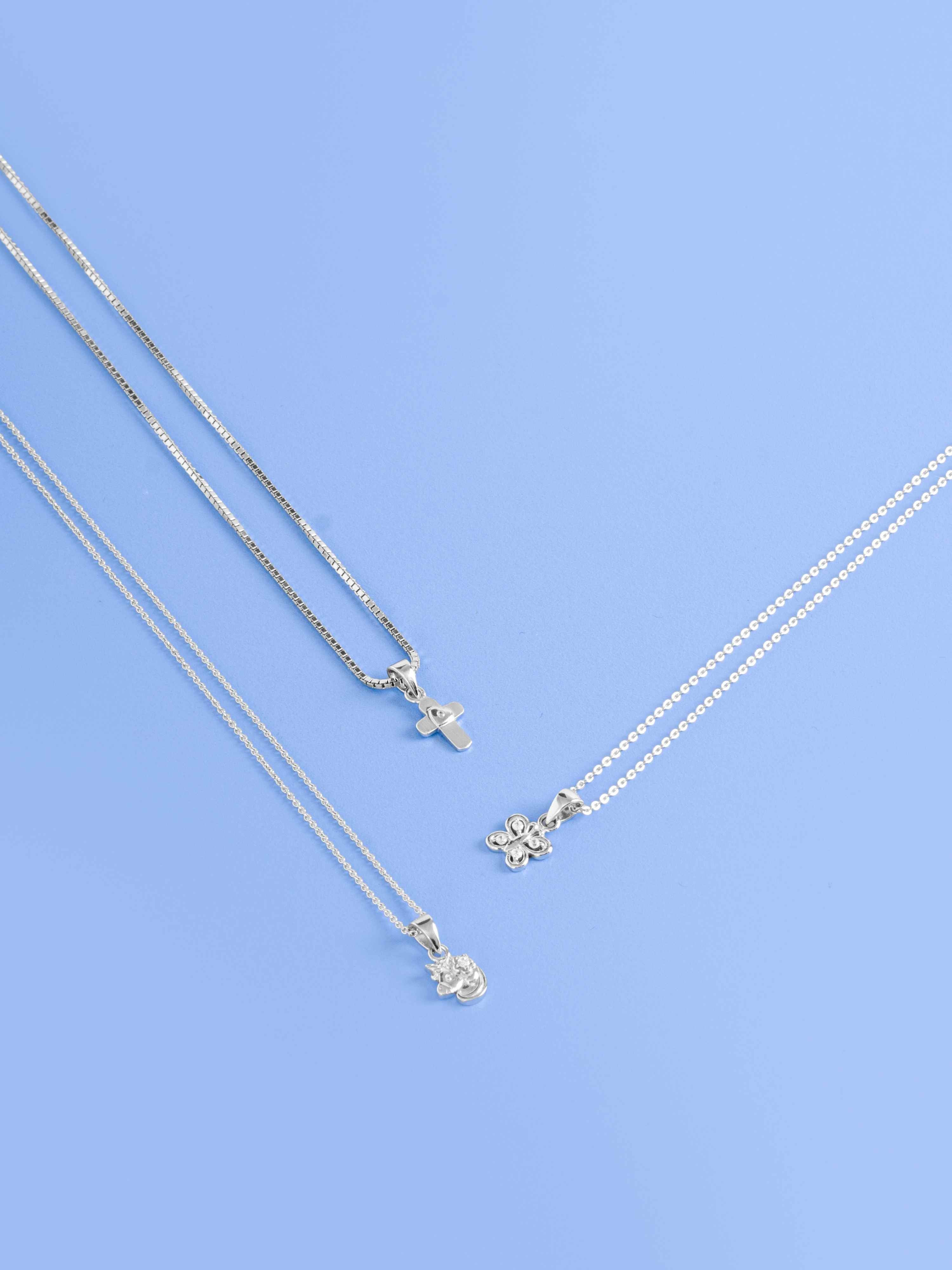 Three sterling silver necklace flat lay on blue surface