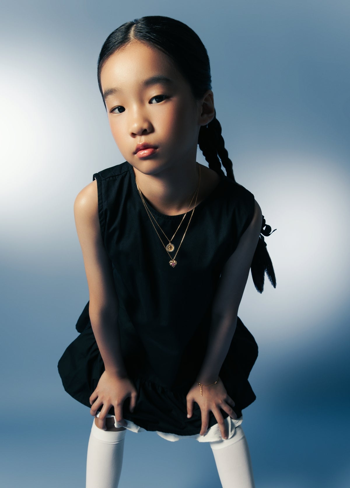 Girl in black dress wearing layered gold necklaces — Cross Twinkle & Ruby Liberty Necklace, Blue Francis