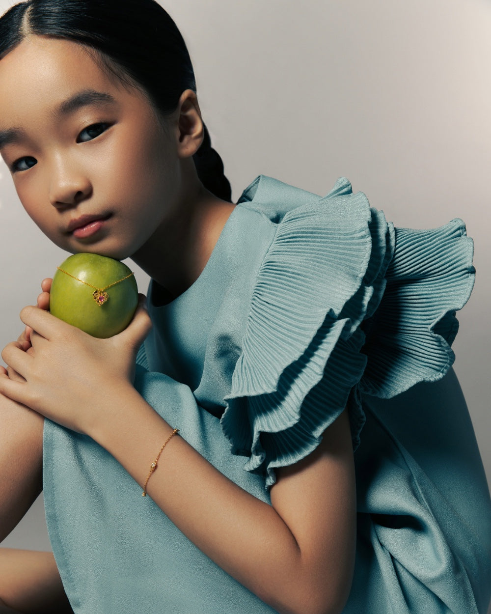 Young girl holding a green apple against a plain background