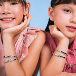 Two girls wearing Blue Francis Melodie Fleur Bangles, including the Melodie Turquoise Fleur Bangle stacked with pink and butter sterling silver flower bracelets