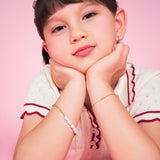 Girl wearing the Melodie Pearl Bracelet, a kids gold bracelet in gold-plated sterling silver with freshwater pearls