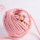 Blue Francis Chelsea Twinkle Heart, gold vermeil heart huggie earrings with pink cubic zirconia on a pink yarn ball