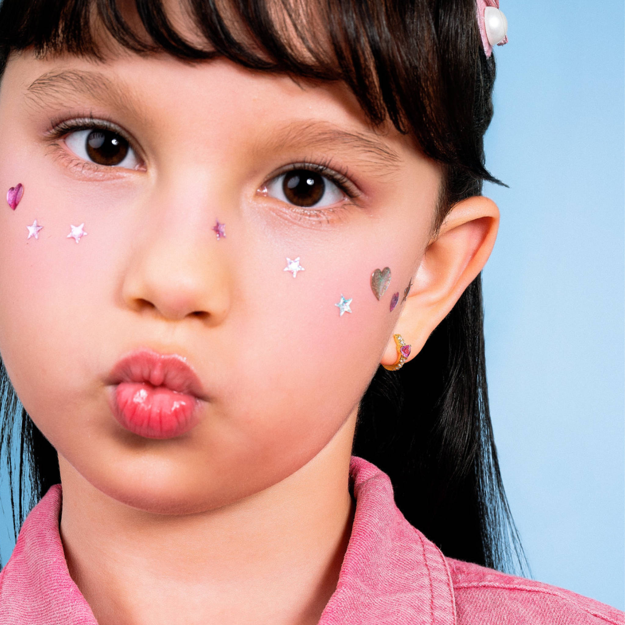 Girl wearing Blue Francis Chelsea Twinkle Heart, gold vermeil heart huggie earrings sized for kids