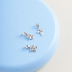 Blue Francis Butterfly, Cross and Unicorn Pendants on flat lay blue surface with cream background