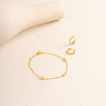 Gold Vermeil Twinkle bracelet and gold vermeil Twinkle hoops on a beige background