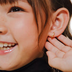 Blue Francis Kids Hoop Earrings in Vermeil 18K Gold called Twinkle Hoops. This is a close-up picture of Blue Francis model wearing a gold vermeil hoop earring with a natural background