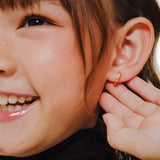 Blue Francis Kids Hoop Earrings in Vermeil 18K Gold called Twinkle Hoops. This is a close-up picture of Blue Francis model wearing a gold vermeil hoop earring with a natural background