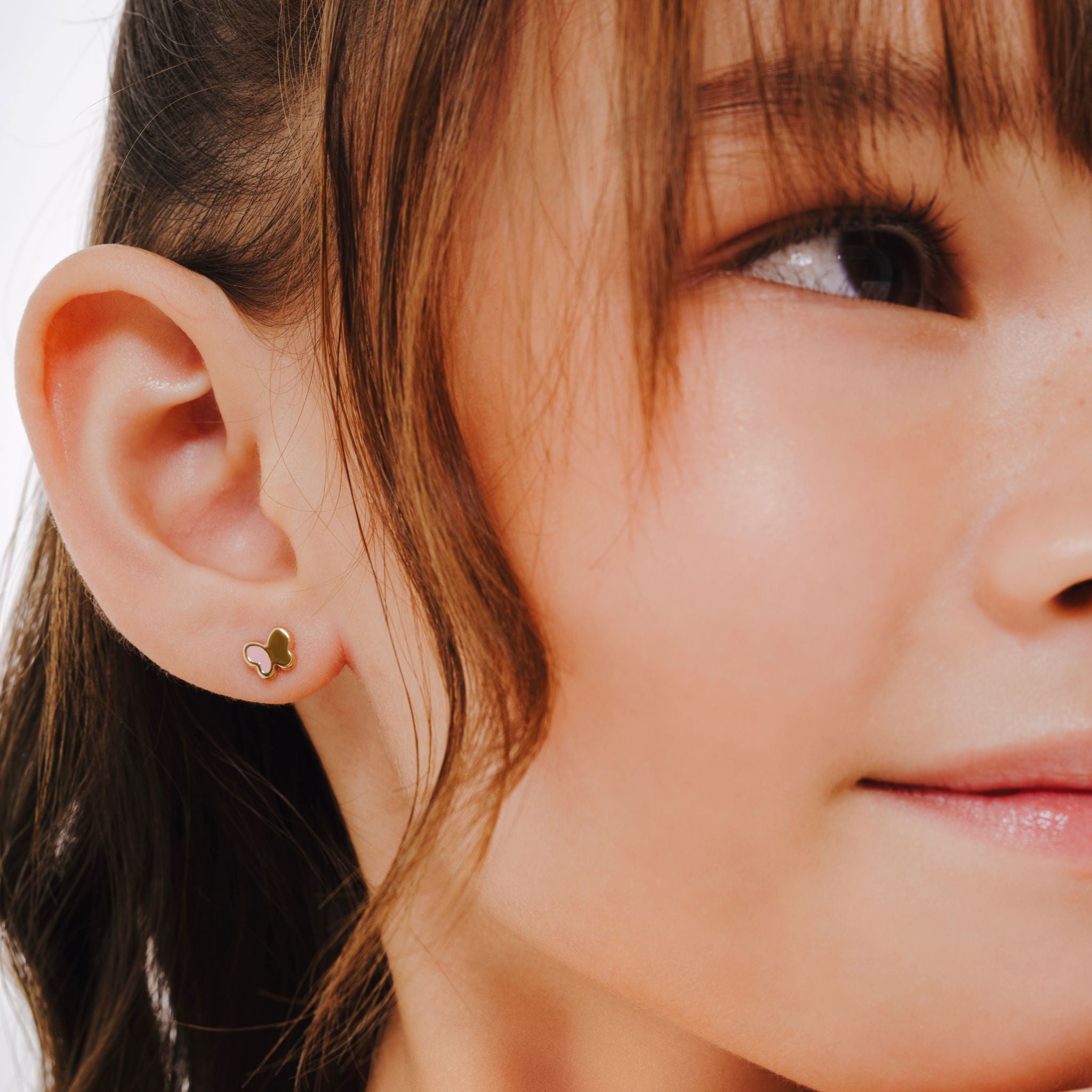 Blue Francis - Kids Stud Earrings - Gold 14K - Pink Hudson Butterfly Bracelet. In the picture is a close-up of Blue Francis model, wearing a butterfly-shaped earring with Pink enamel