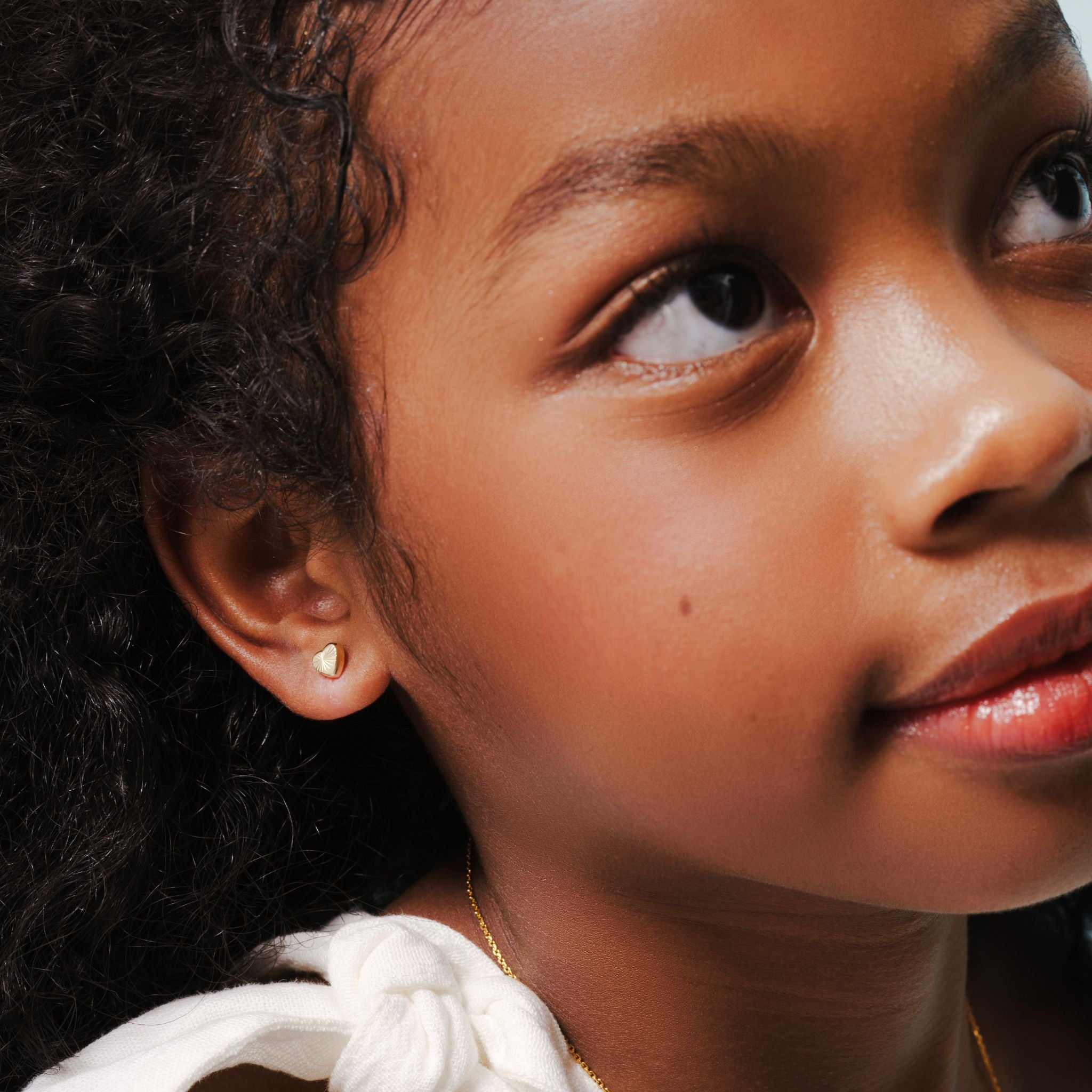 Blue Francis - Kids Stud Earrings - Gold Solid 14K - Soho Heart Studs. Close-up picture of a model with Solid Gold earrings for kids. 