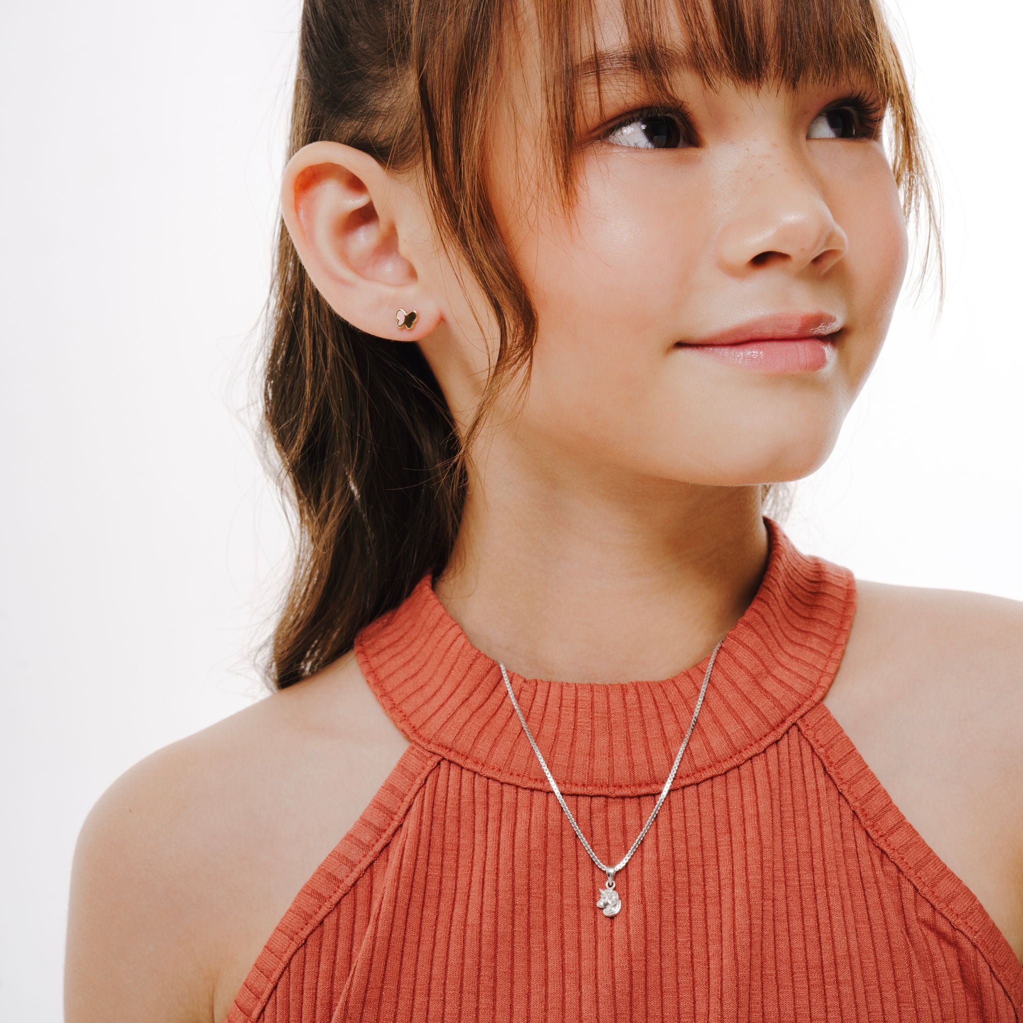 A teen wearing a orange halter top and silver necklace with Brooklyn Unicorn Pendant on a white background.
