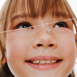 Blue Francis - Tweens Chain in Sterling Silver and a Brooklyn cross pendant on Cable Chain. This is a close-up picture of a child's face with a necklace featuring a cross pendant and chain cable. 