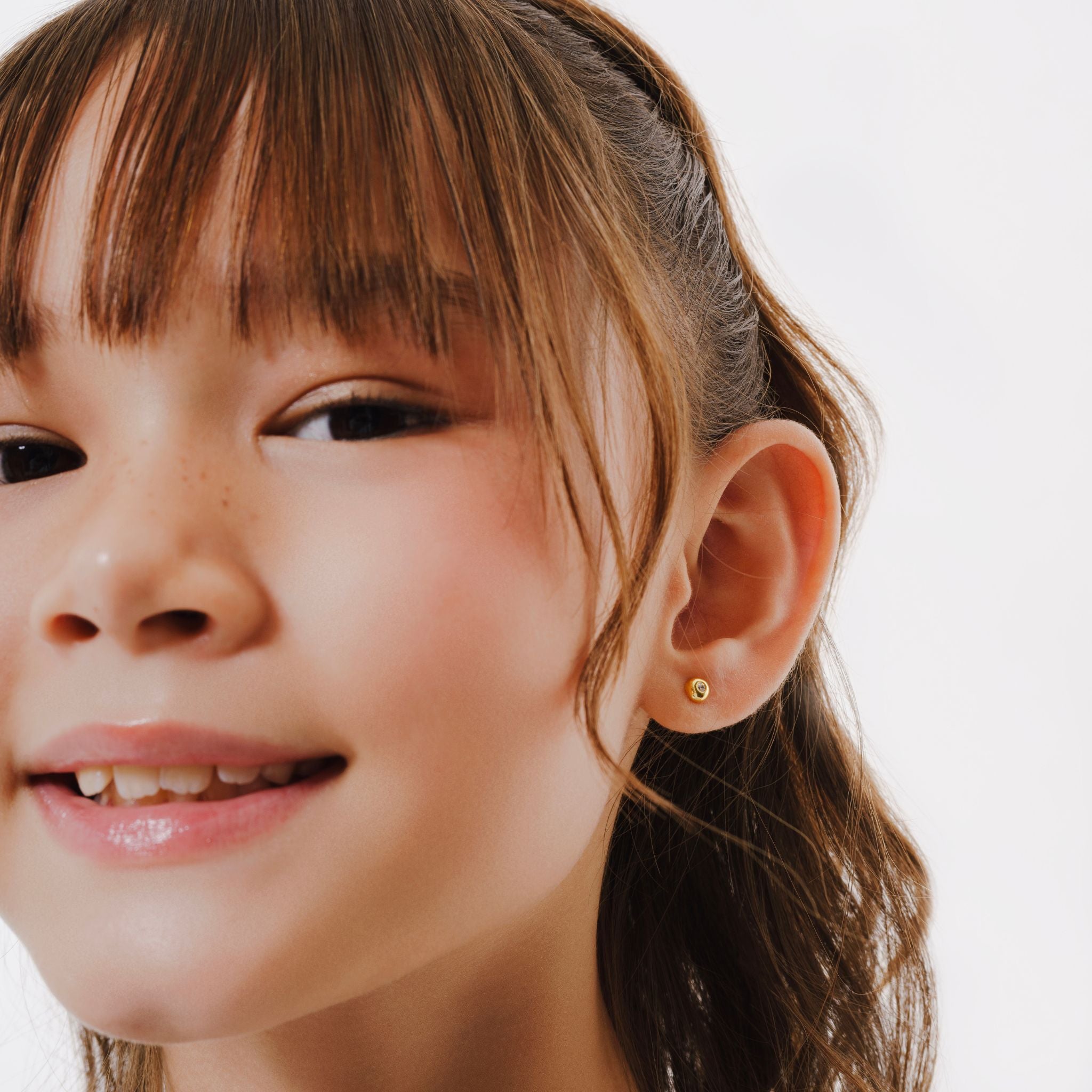Blue Francis Tween Stud Earrings - Twinkle Circle Studs. This is a close-up of Blue Francis model wearing a Vermeil 18K Gold earring, on a white background.