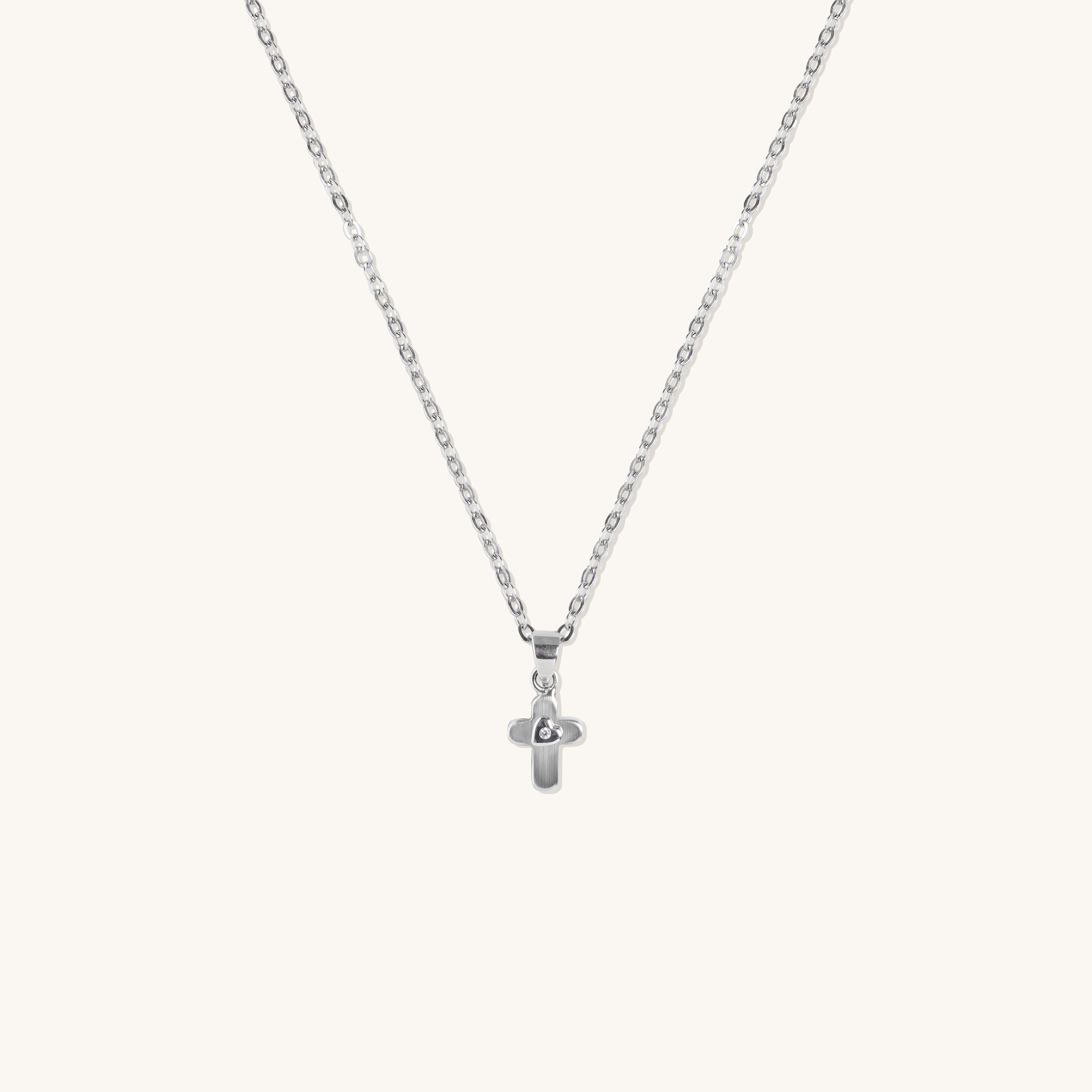 Brooklyn Cross Necklace in sterling silver with cubic zirconia and small heart center, displayed on neutral background for product clarity.