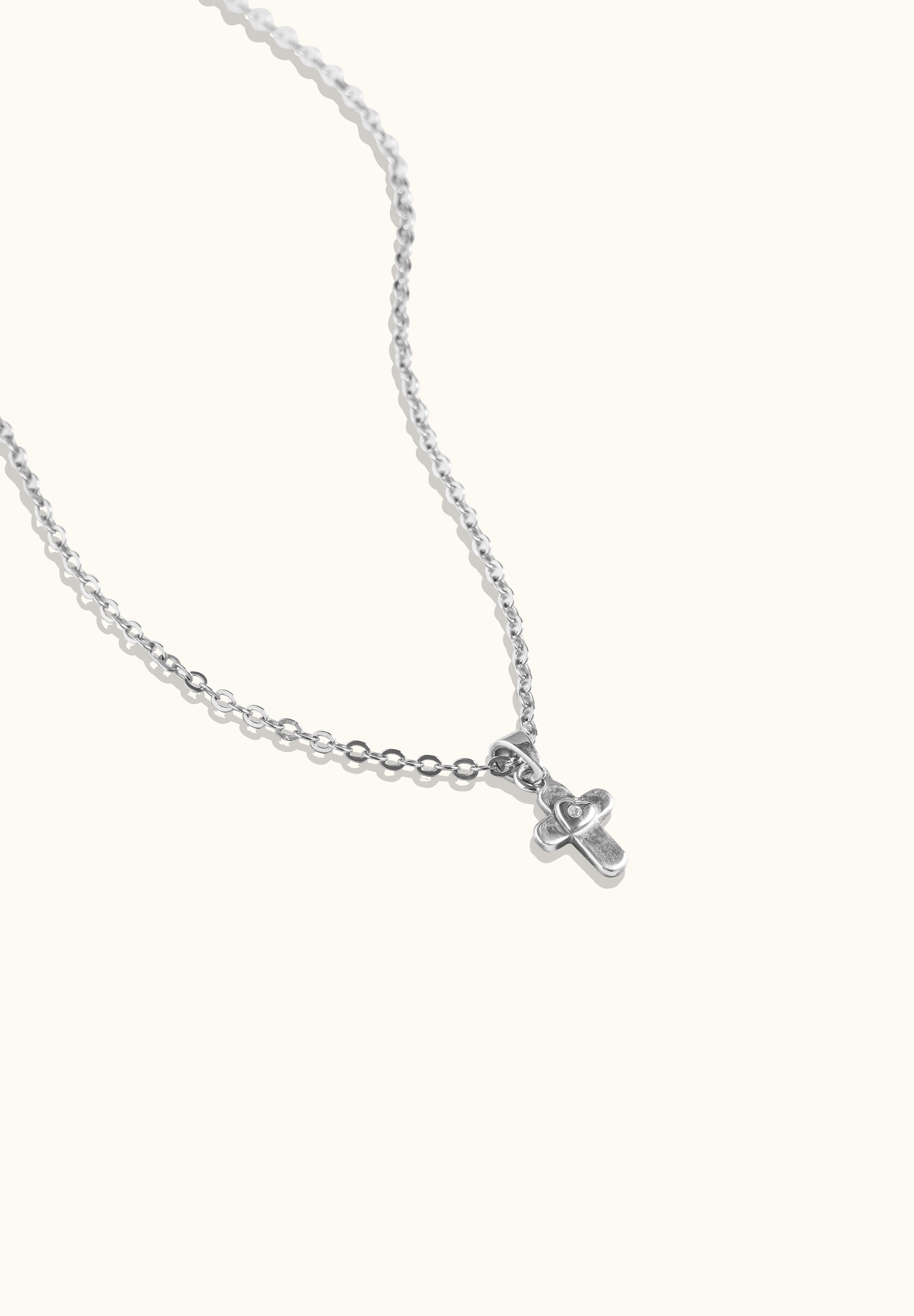 Brooklyn Cross Necklace in sterling silver and cubic zirconia with heart center, photographed from side angle on neutral background to show shape detail.