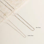 Close-up of box chain and cable chain on a textured beige surface - Blue Francis