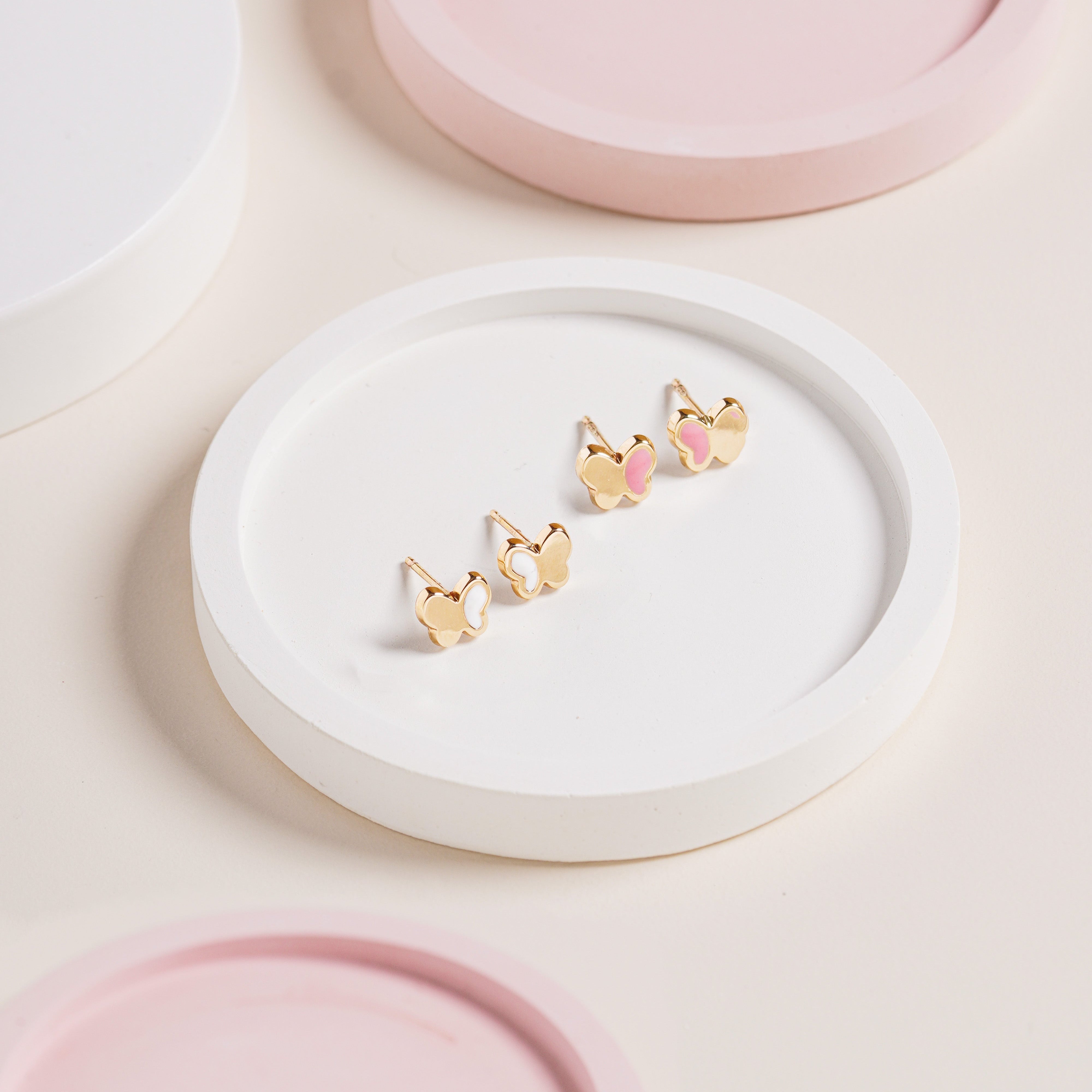 Blue Francis Pink Hudson Butterfly Studs crafted in 14K gold with pink enamel wings, displayed on a white round tray with pastel pink styling.