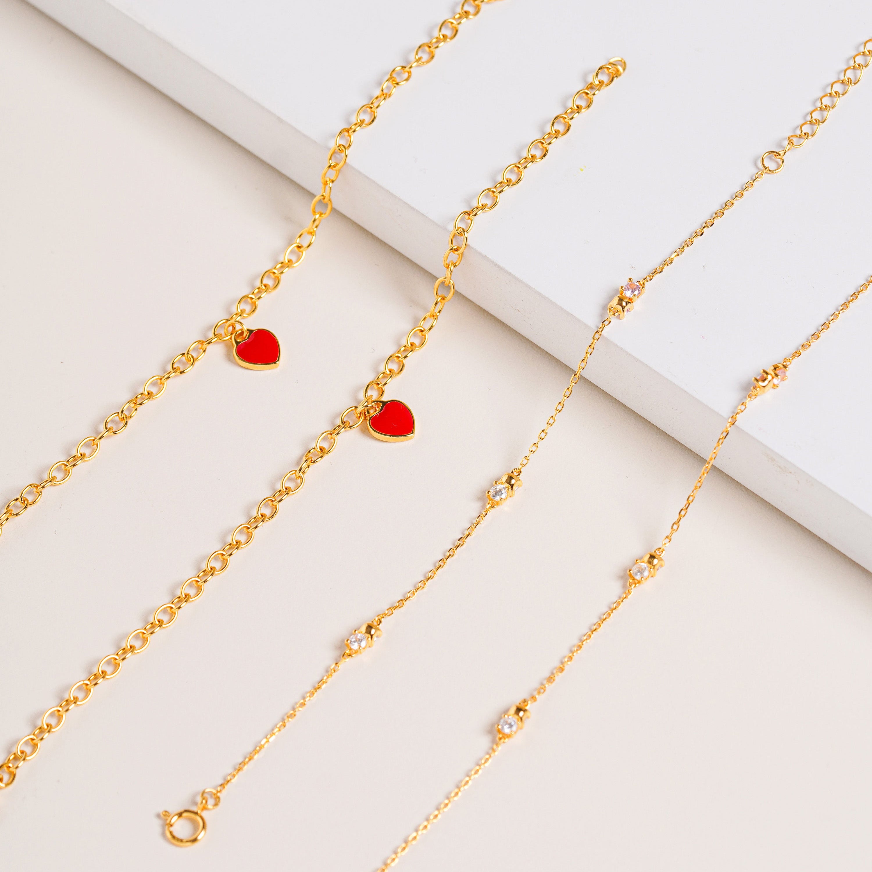 Vermeil chain bracelet with sparkling Cubic Zirconia stones, pictured together with Red Central Heart Bracelet on cream background.
