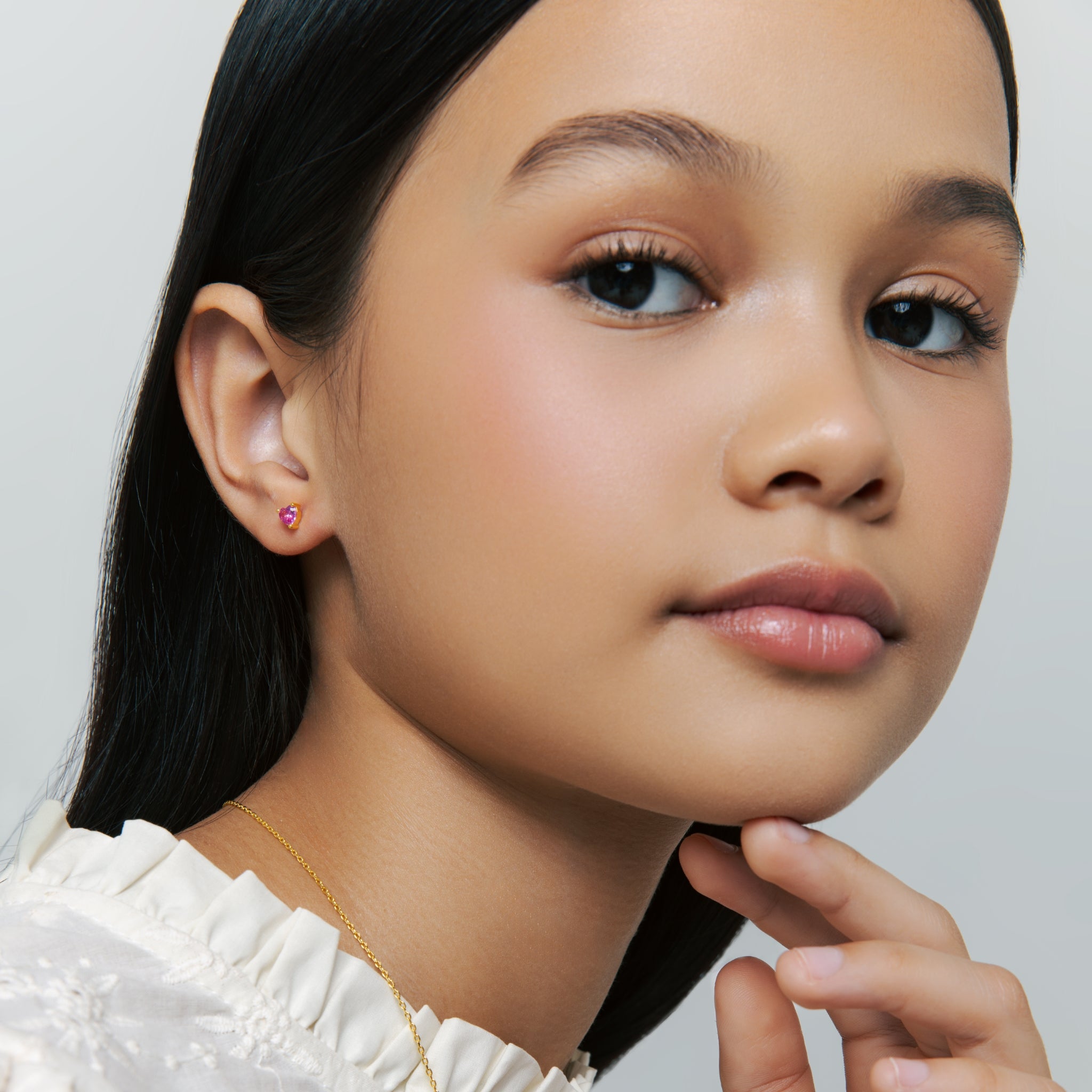 Model wears Ruby Liberty Stud Earrings in vermeil with ruby corundum stones and prong setting, smiling gently against a soft neutral background for detail.