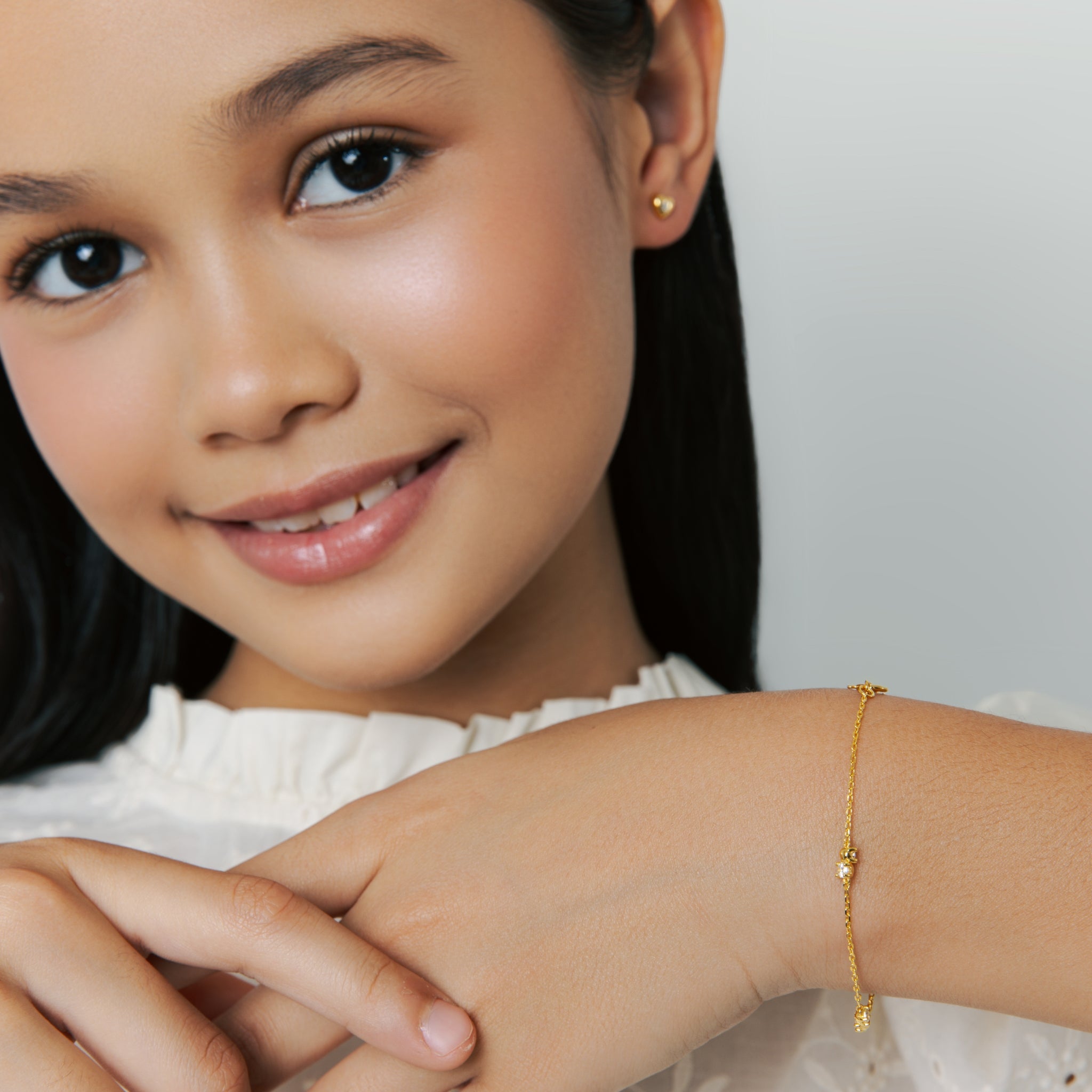 Blue Francis Twinkle Bracelet in gold vermeil with three sparkling cubic zirconia stones, shown on a model wearing a white ruffled blouse with neutral background.